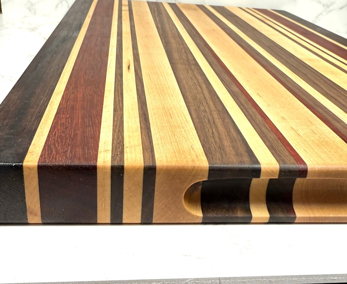 "The OKI 25 – handcrafted cutting board made from Wenge, Black Walnut, Padauk, and Maple."
