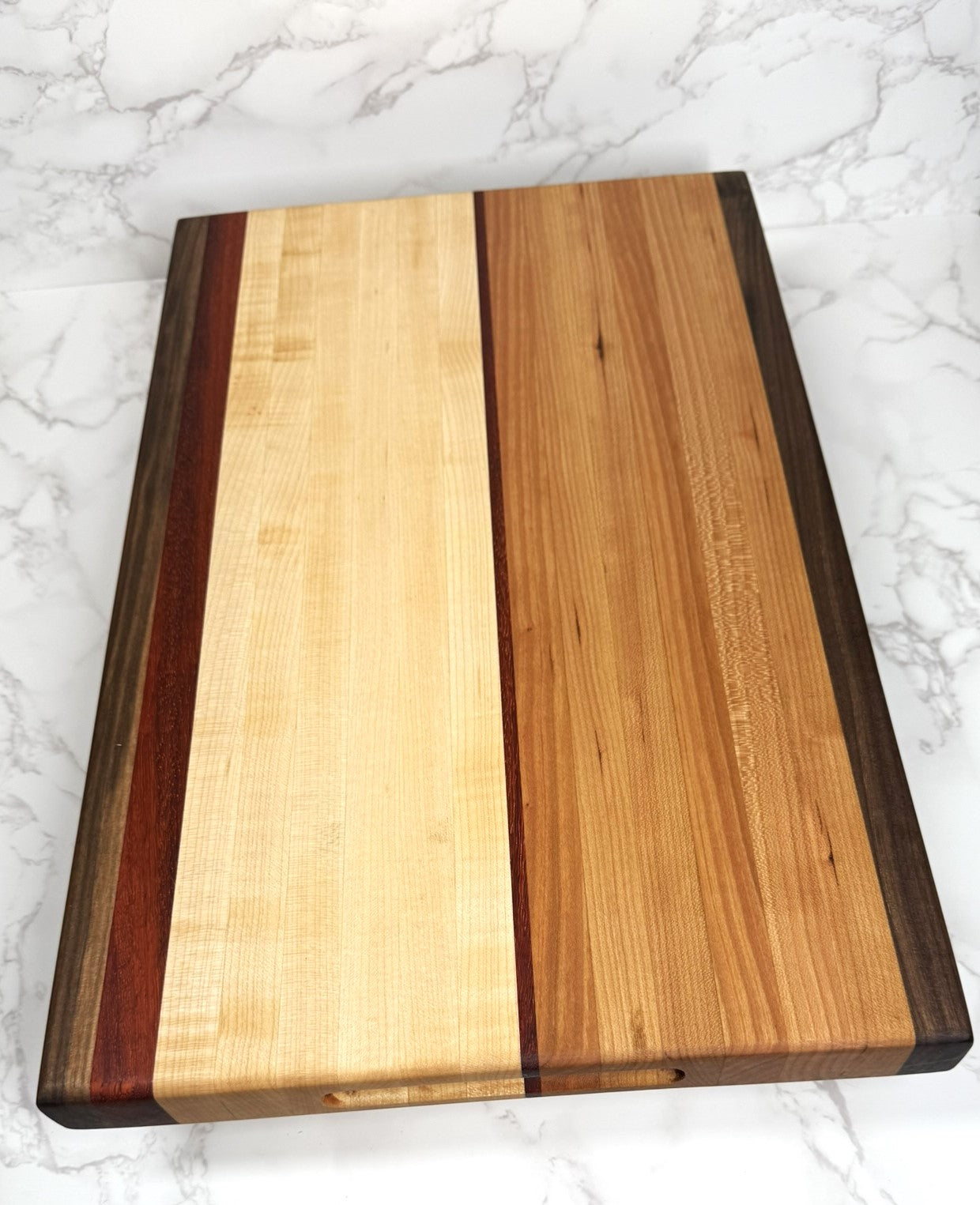 "The Arnold Palmer edge grain cutting board showcasing Black Walnut, Maple, Cherry, and Padauk woods"
