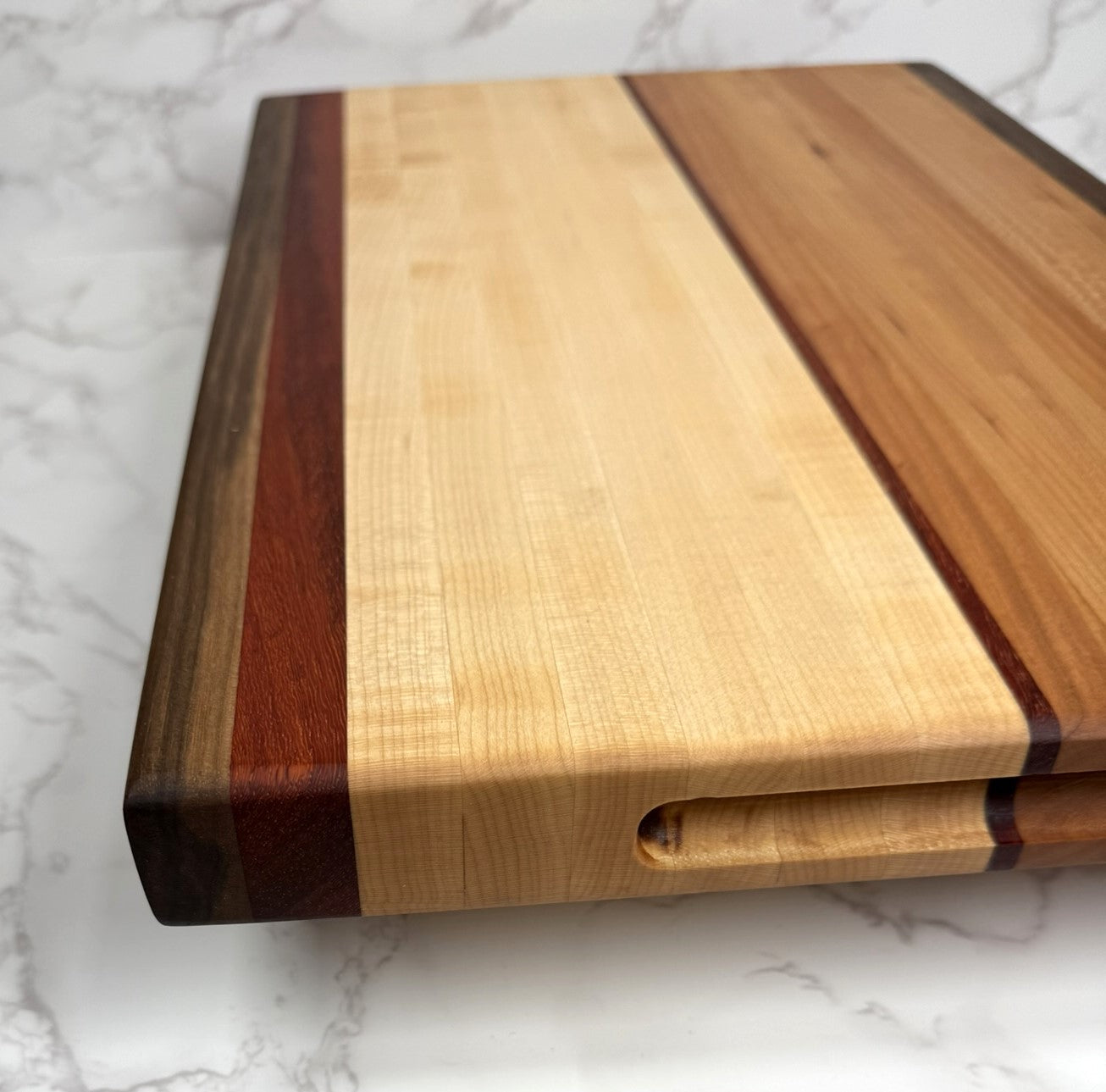 "The Arnold Palmer edge grain cutting board showcasing Black Walnut, Maple, Cherry, and Padauk woods"