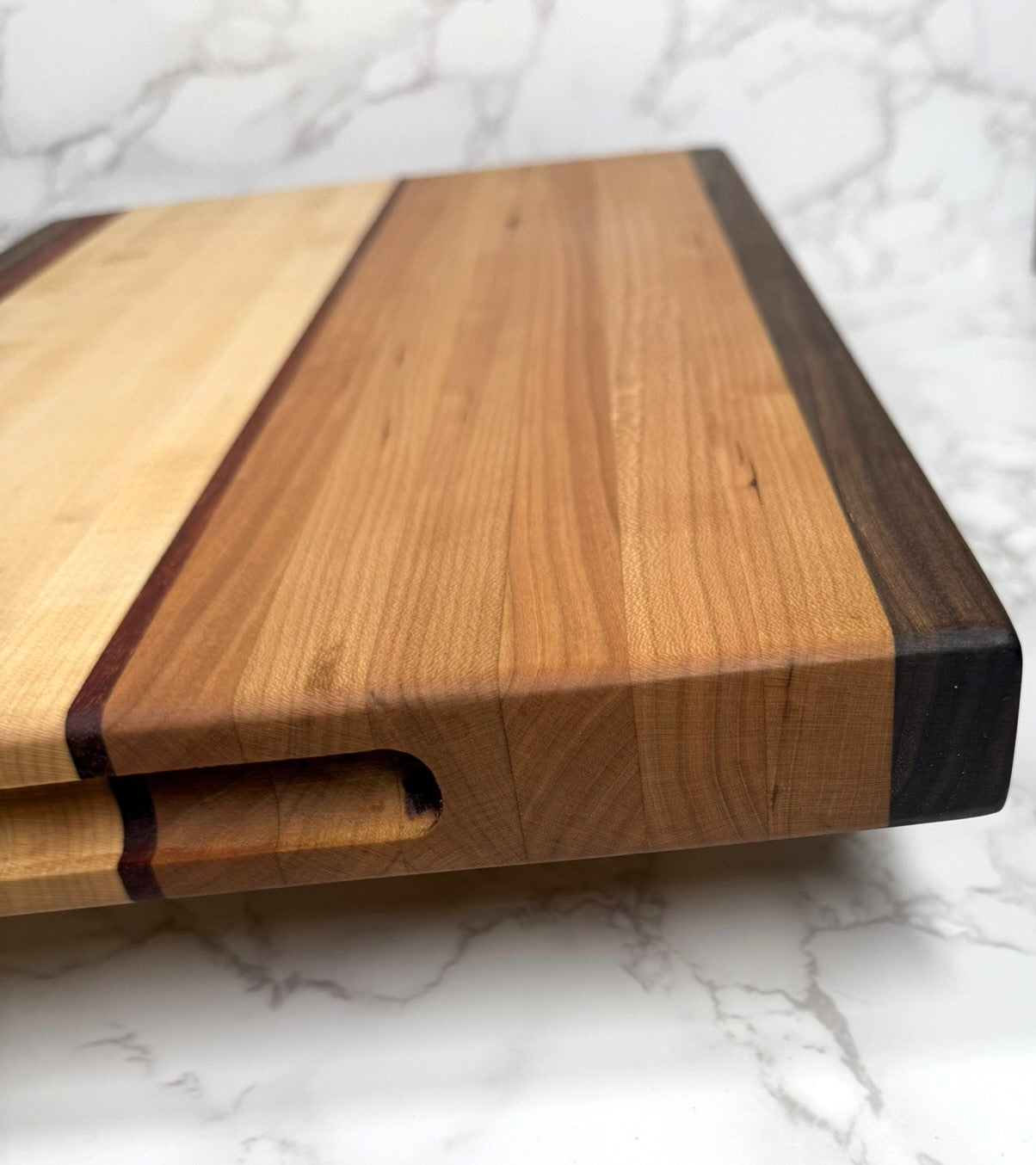 "The Arnold Palmer edge grain cutting board showcasing Black Walnut, Maple, Cherry, and Padauk woods"