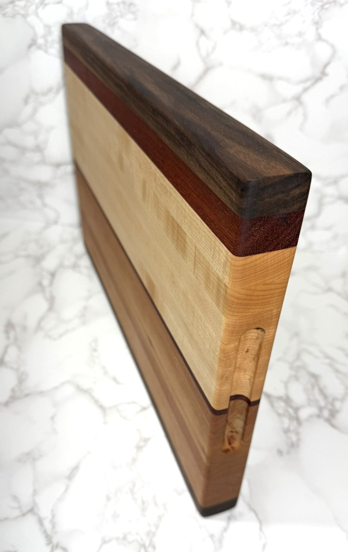 "The Arnold Palmer edge grain cutting board showcasing Black Walnut, Maple, Cherry, and Padauk woods"