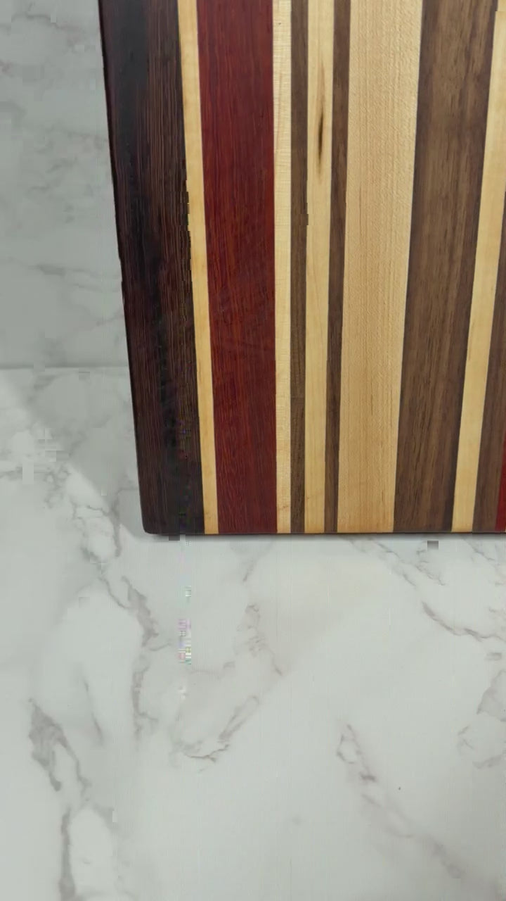 "The OKI 25 – handcrafted cutting board made from Wenge, Black Walnut, Padauk, and Maple."
